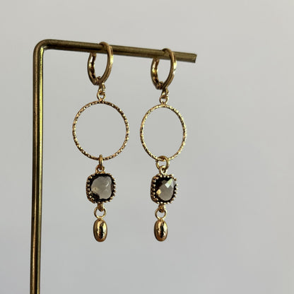 14k vergulde oorbellen Carien met een bewerkte ronde ring, vierkante gefacetteerde grijze kristalsteen en klein goud bedeltje.