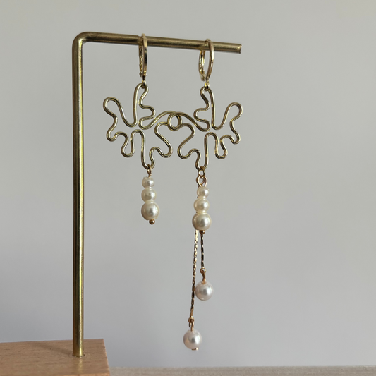 Gouden asymmetrische oorbellen Clarisse met abstracte hangers en witte parels.