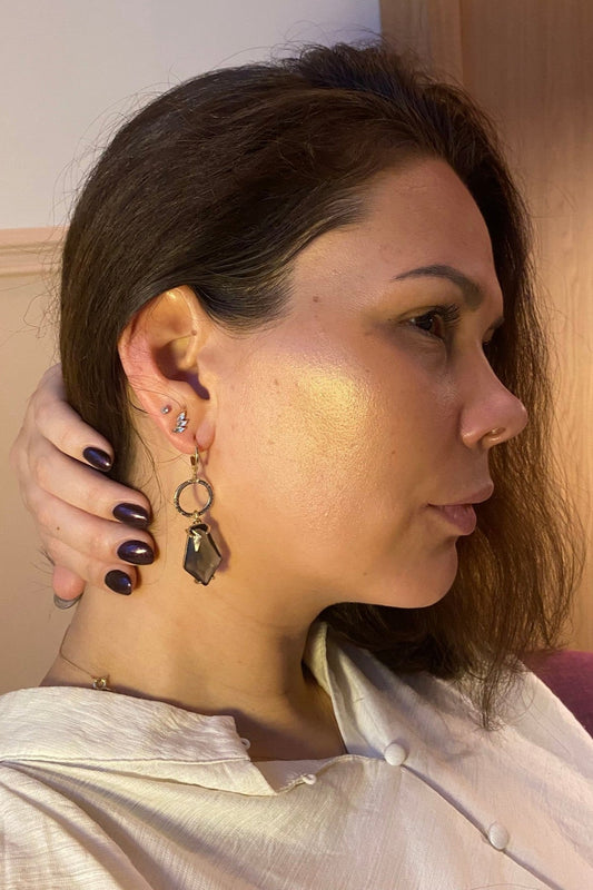 Model met Handgemaakte 14k vergulde Lellebel oorbellen met gehamerde vergulde ringen en een grotere grijze glasbedel 