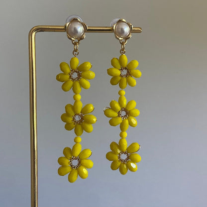 Handgemaakte oorbel met 3 gele  bloemen onder elkaar van glanzende kralen en een 14K vergulde steker met parel in de vorm van een bloem.