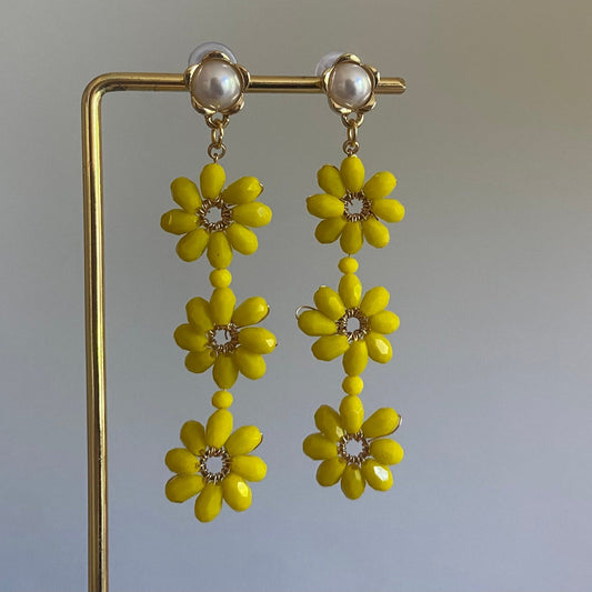 Handgemaakte oorbel met 3 gele  bloemen onder elkaar van glanzende kralen en een 14K vergulde steker met parel in de vorm van een bloem.