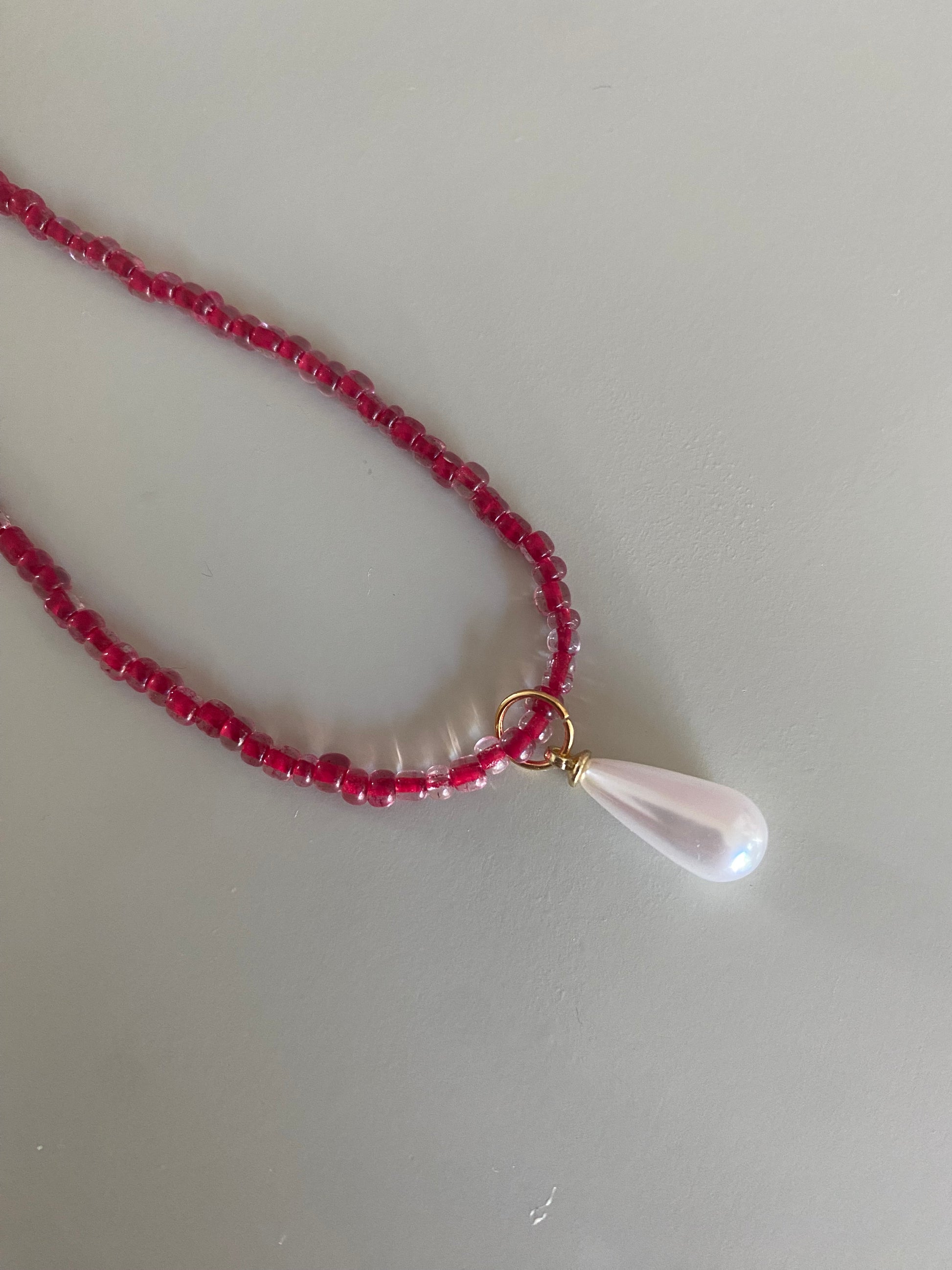Closeup van Rode glaskralen of rijstkralen ketting met een parel bedel 