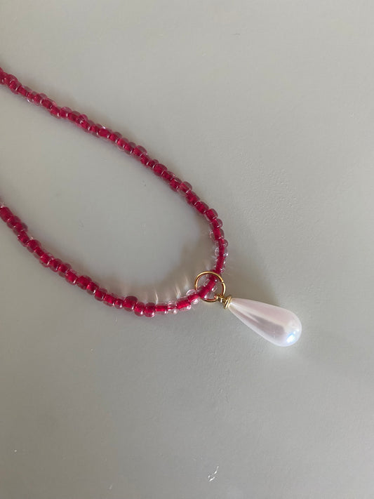Closeup van Rode glaskralen of rijstkralen ketting met een parel bedel 
