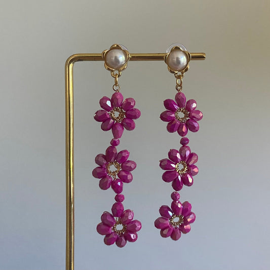 Handgemaakte oorbel met 3 roze  bloemen onder elkaar van glanzende kralen en een 14K vergulde steker met parel in de vorm van een bloem.
