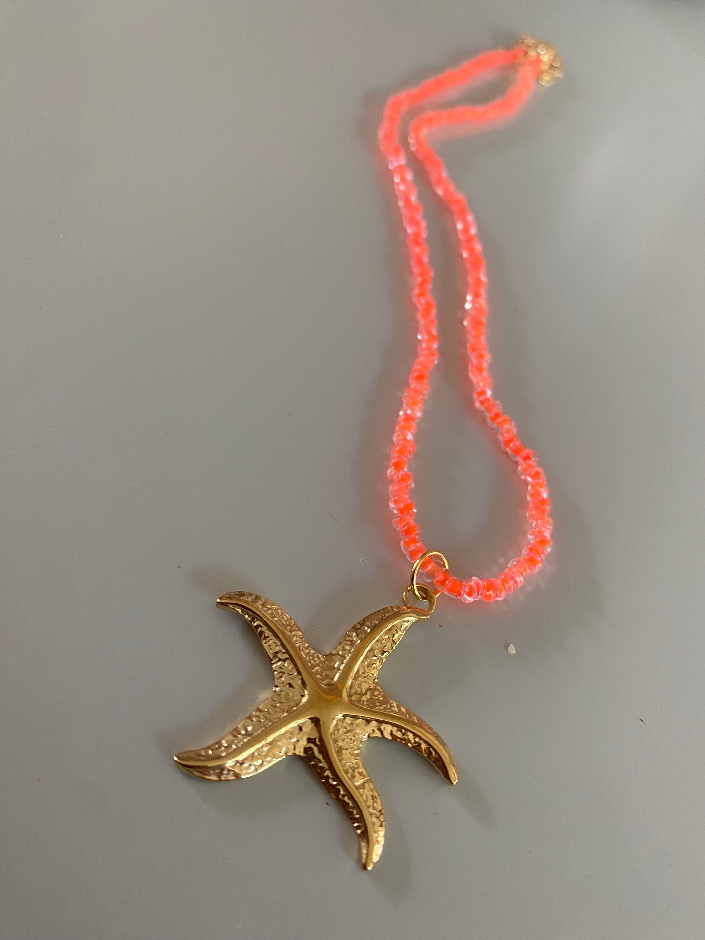 Neonoranje Ketting van rijstkralen of glaskralen met daaraan een rvs zeester