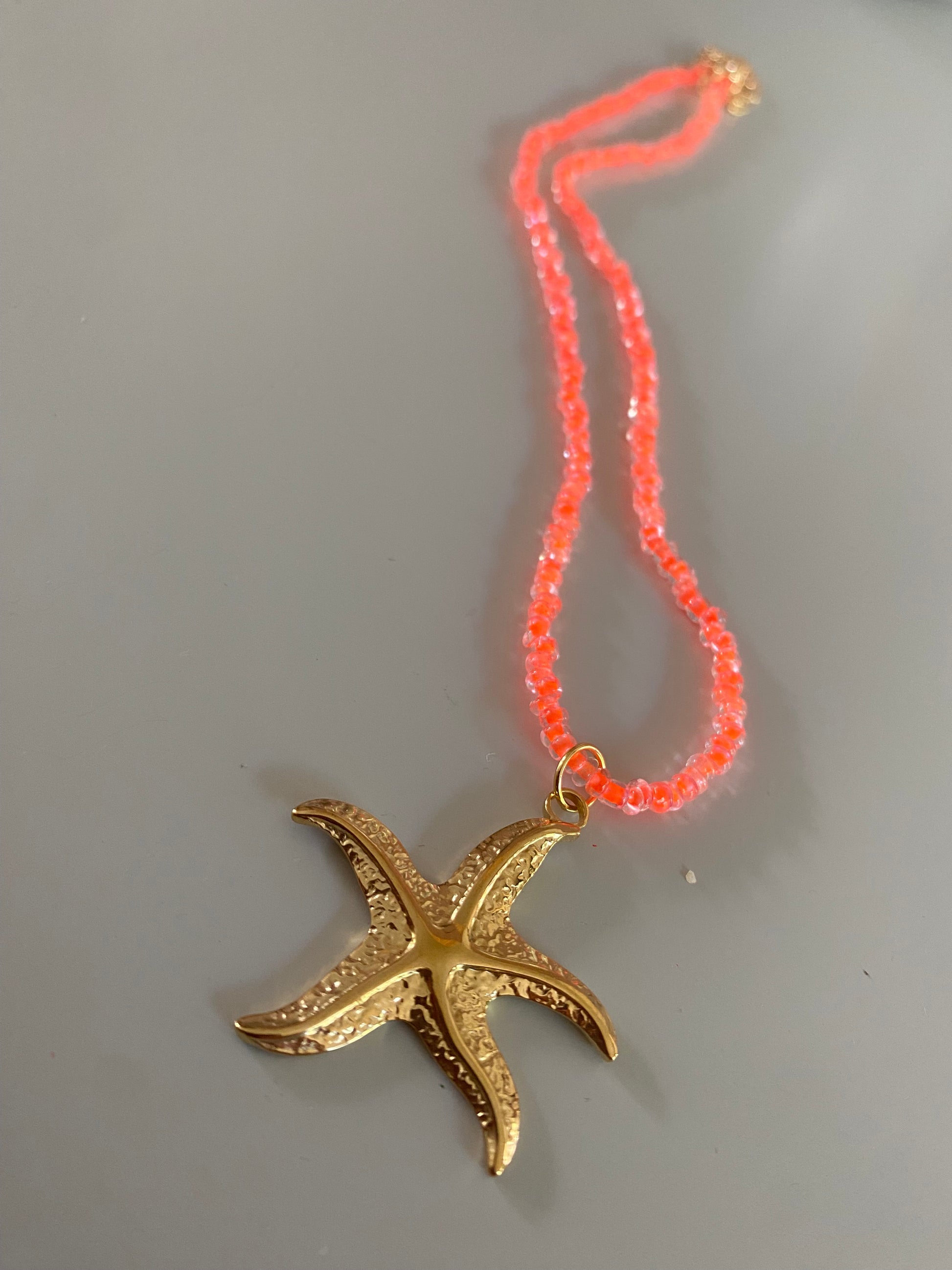 Neonoranje Ketting van rijstkralen of glaskralen met daaraan een rvs zeester