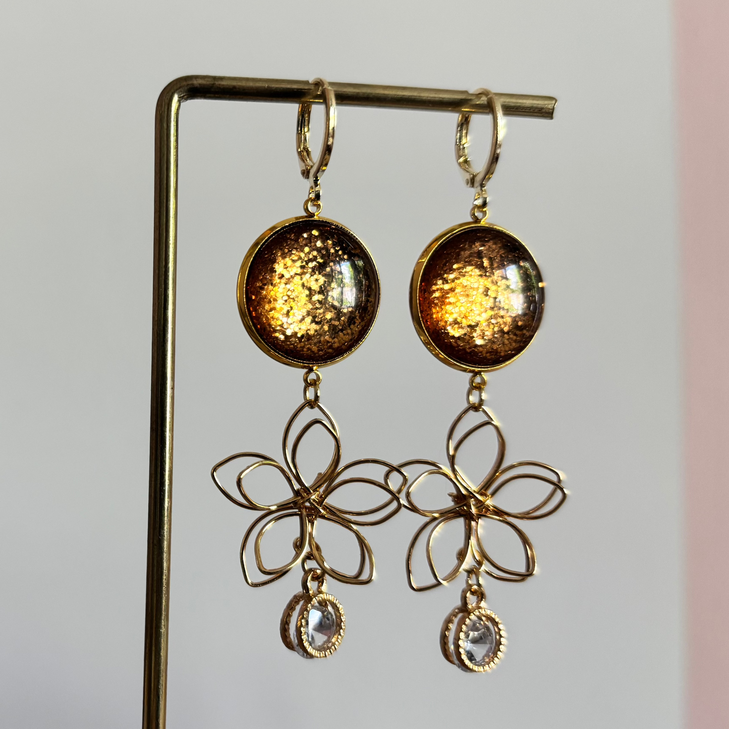 Symmetrische 14k vergulde oorbellen Elly met bronskleurige glitterstenen, gouden draadbloemen en fonkelende zirkonia details.