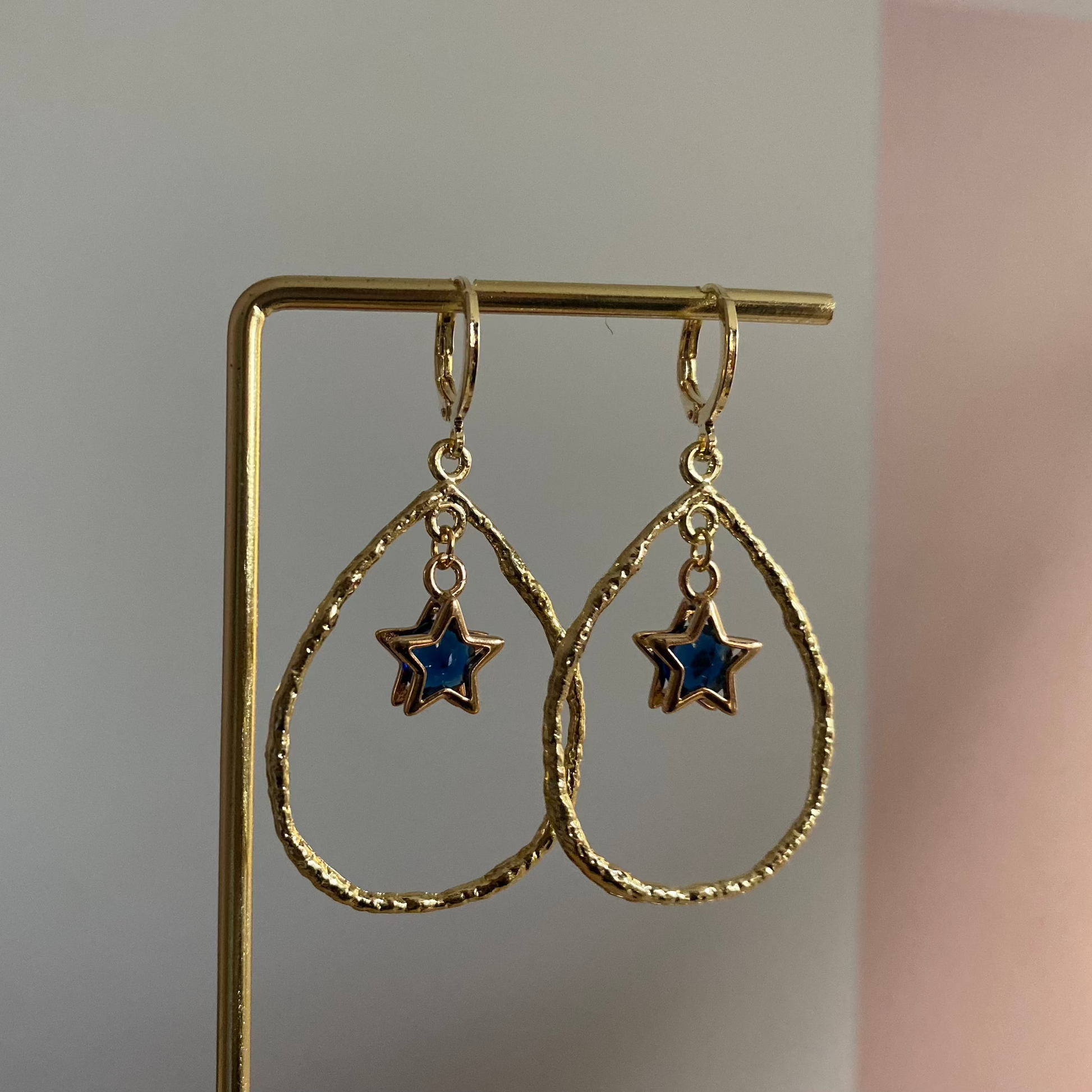 Een foto van de Estelle oorbellen van lellebel sieraden. 14k vergulde oorbel met ster en steentje in open ring, feestelijke lengte van 4 cm.