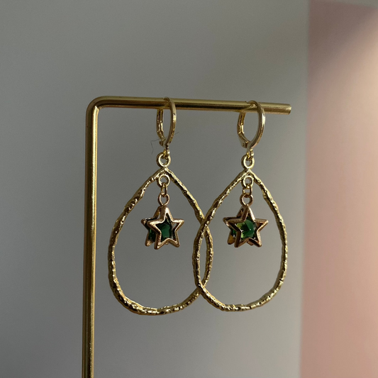 Een foto van de Estelle oorbellen van lellebel sieraden. 14k vergulde oorbel met ster en steentje in open ring, feestelijke lengte van 4 cm.