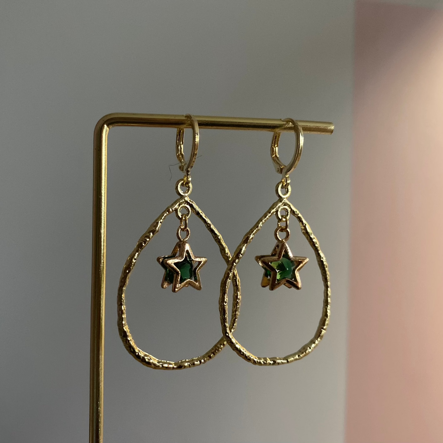 Een foto van de Estelle oorbellen van lellebel sieraden. 14k vergulde oorbel met ster en steentje in open ring, feestelijke lengte van 4 cm.