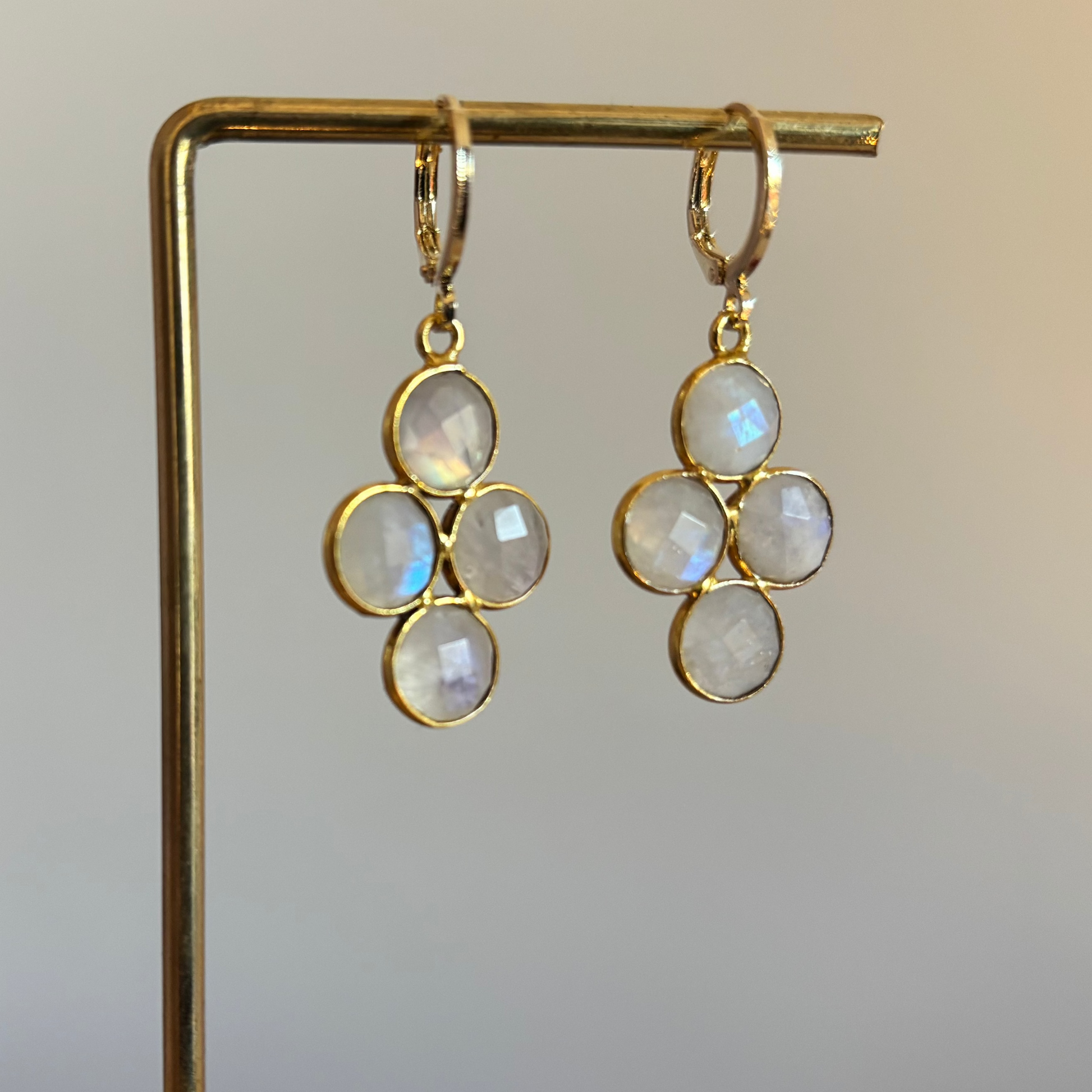 "Kleine gouden oorbellen met een ronde witte maansteen die verdeeld is in vier gelijke vlakken."