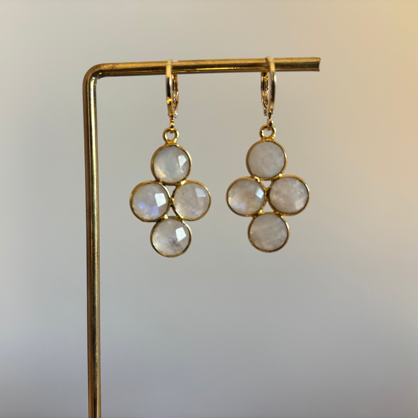 "Kleine gouden oorbellen met een ronde witte maansteen die verdeeld is in vier gelijke vlakken."