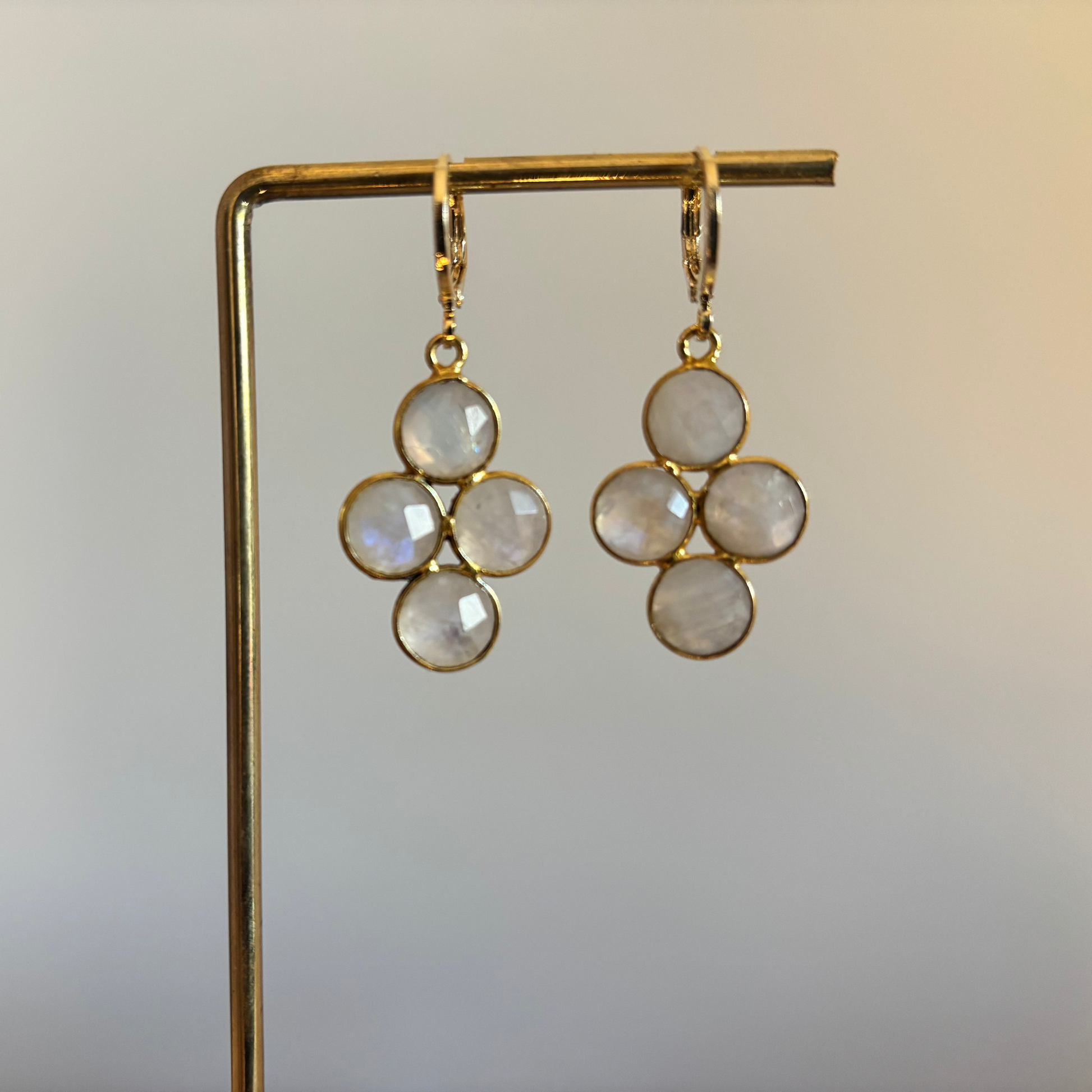 "Kleine gouden oorbellen met een ronde witte maansteen die verdeeld is in vier gelijke vlakken."