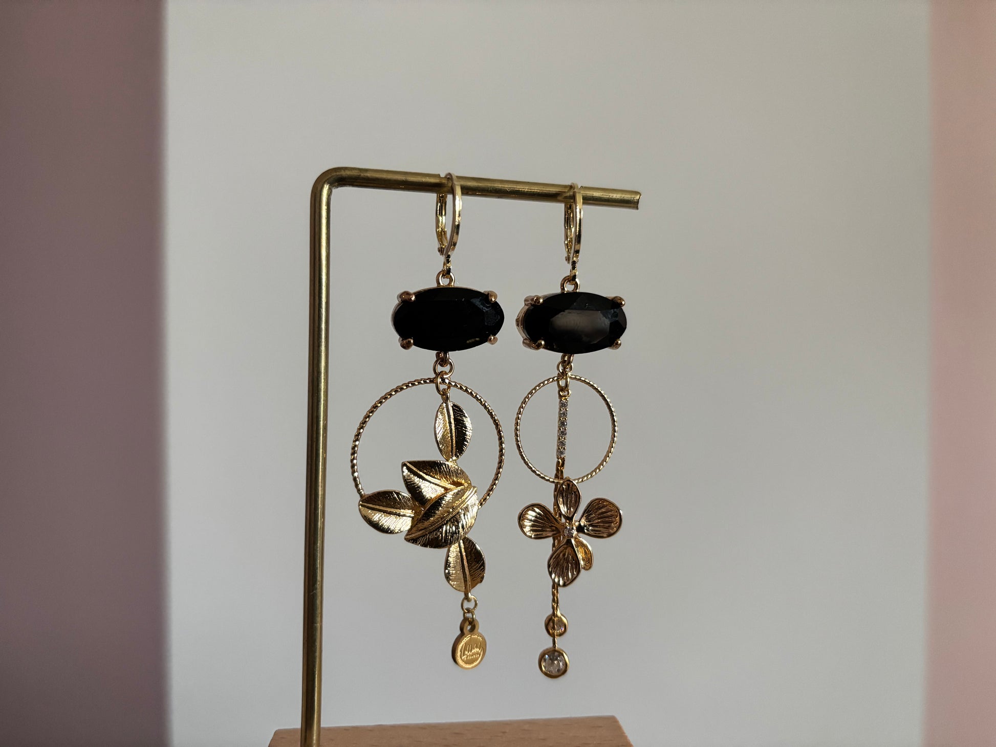 Asymmetrische 14K vergulde oorbellen met glazen bedels en gouden bloem- en bladmotieven.