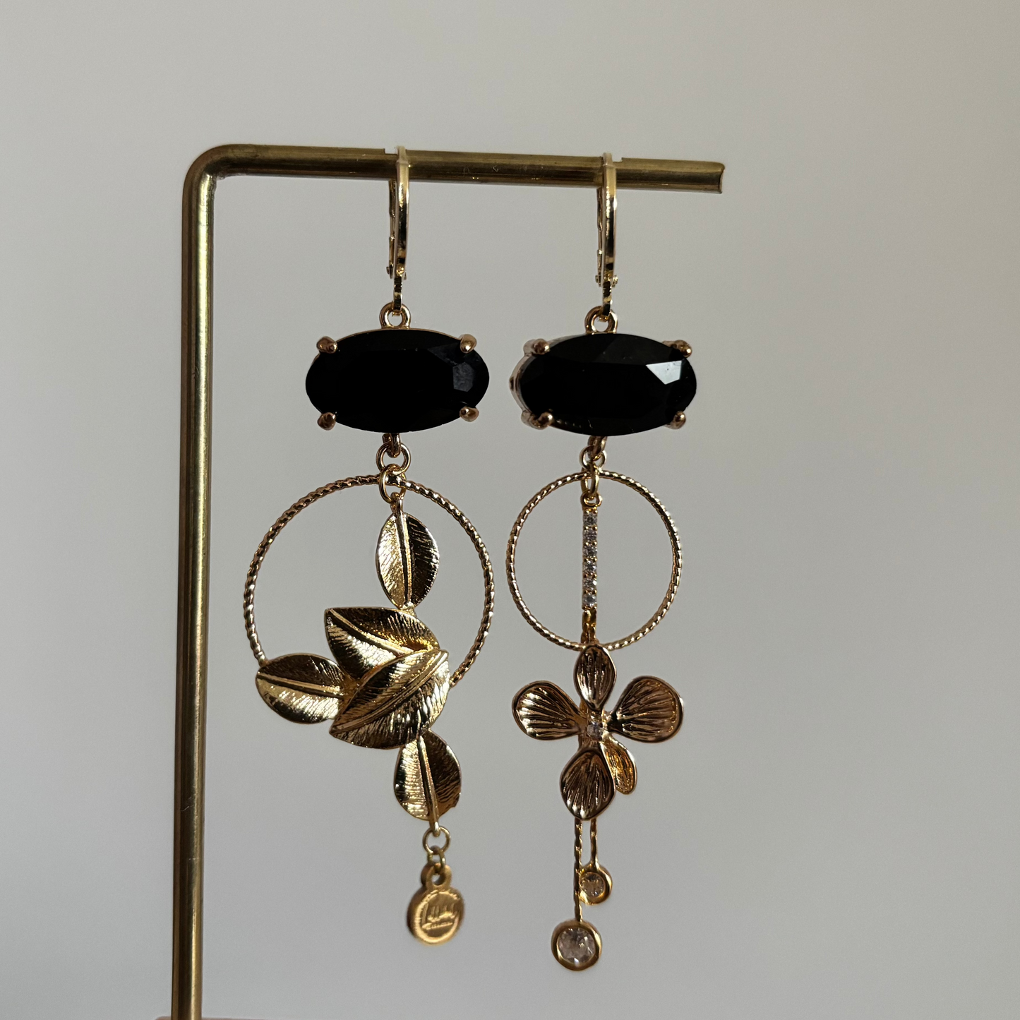 Asymmetrische 14K vergulde oorbellen met glazen bedels en gouden bloem- en bladmotieven.
