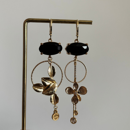 Asymmetrische 14K vergulde oorbellen met glazen bedels en gouden bloem- en bladmotieven.