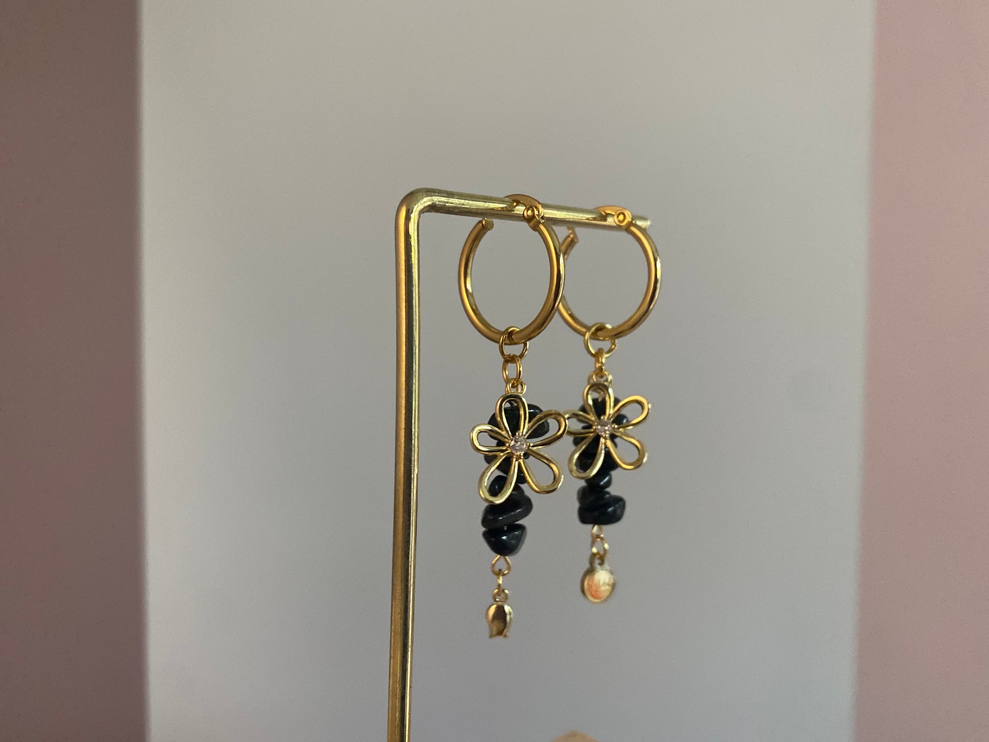 Handgemaakte vergulde gouden oorbellen bestaande uit RVS hoops met daaraan zwarte natuurstenen met een 14K vergulde bloembedel met ingelegde zirkonia.