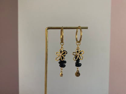 Handgemaakte vergulde gouden oorbellen bestaande uit RVS hoops met daaraan zwarte natuurstenen met een 14K vergulde bloembedel met ingelegde zirkonia.