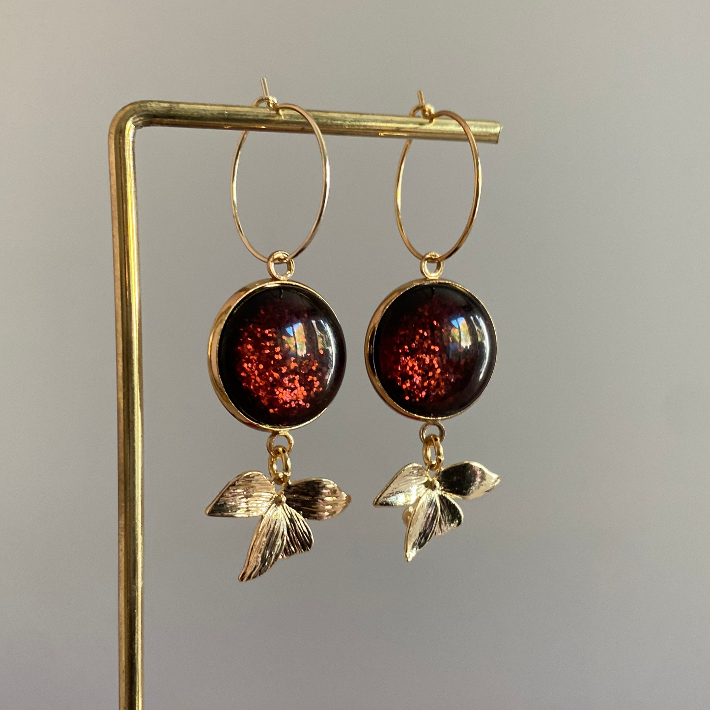 Symmetrische 14k vergulde oorbellen met roodbruine glitter cabochon, minimalistische ring en bladaccent — feestelijke en elegante uitstralin