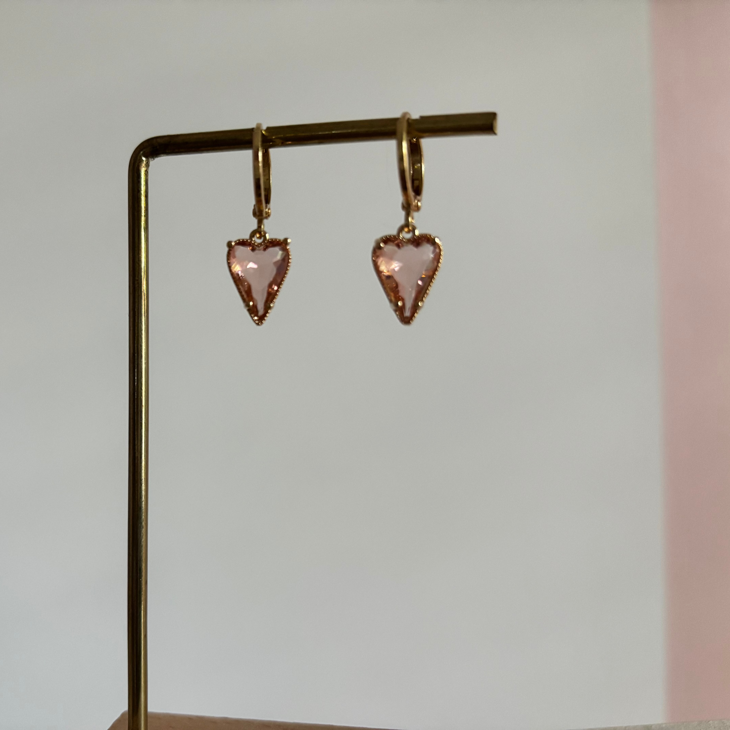 Symmetrische goudkleurige oorbellen Hart champagne aan een rekje, bestaande uit kleine ronde creolen met een hangende bedel in de vorm van een champagnekleurig kristallen hart.