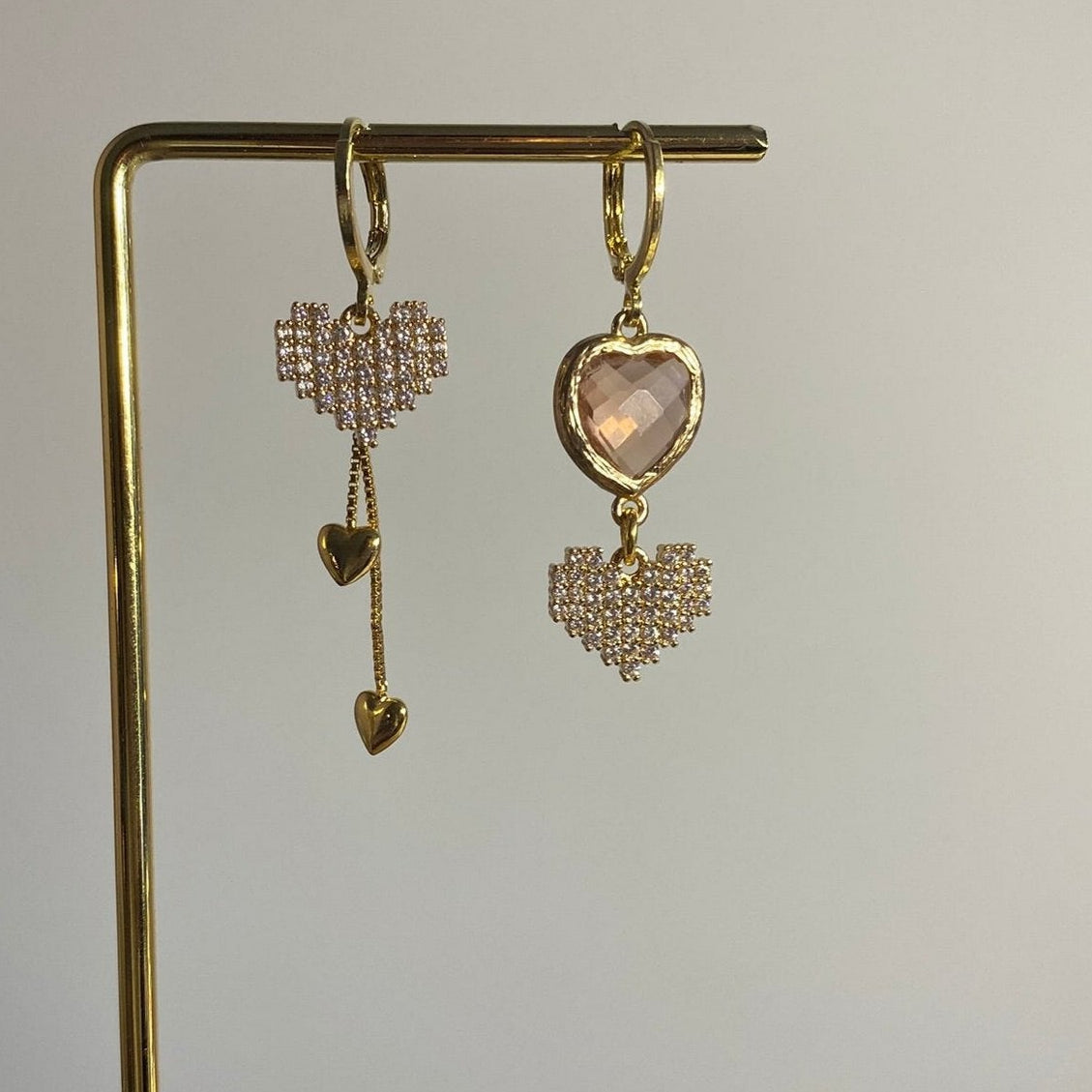 Asymmetrisch handgemaakt paar met 14k vergulde gouden materialen waaronder kleine hangende hartjes, zirkonia hartjes en een champagne glasbedel.