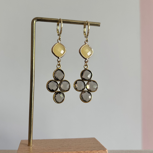 Gouden oorbellen Holly met een ruitvormige gele steen en een hanger van vier taupekleurige facetgeslepen steentjes op een standaard