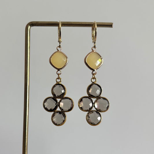 Gouden oorbellen Holly met een ruitvormige gele steen en een hanger van vier taupekleurige facetgeslepen steentjes op een standaard