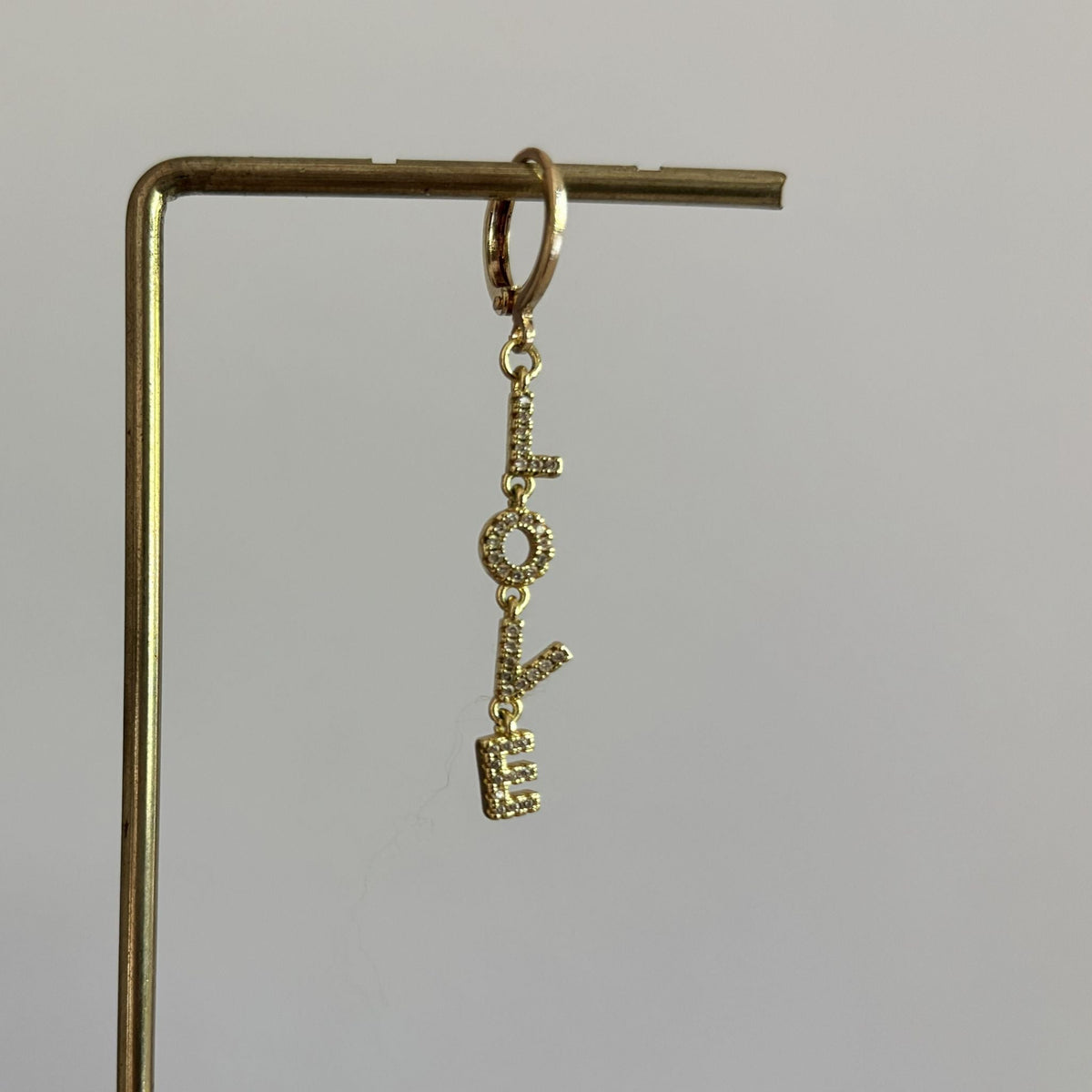 14k vergulde losse oorring Earparty Love met een verticaal hangende 'LOVE' bedel ingezet met heldere zirkonia steentjes.
