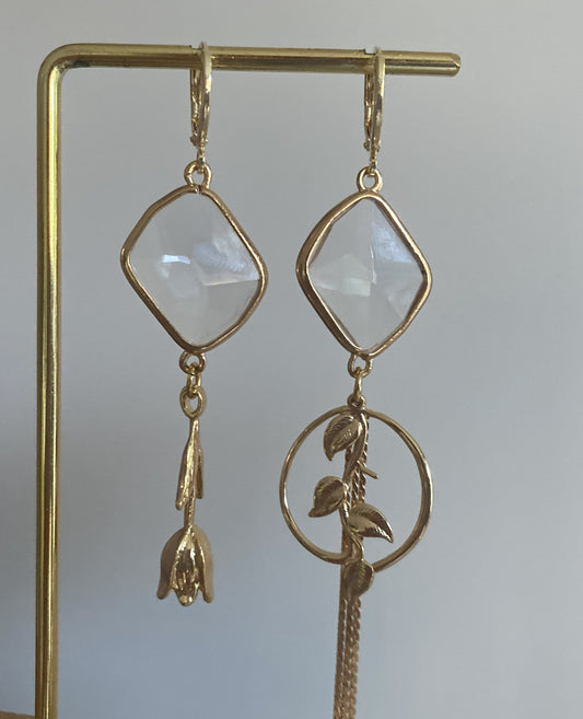 asymmetrisch paar oorbellen, twee verschillende oorbellen. Éen met een 14k vergulde roos andere met een bedel met bladeren ook 14k. Doorzichtige glazen bedel erboven