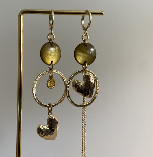 Asymmetrische 14k vergulde oorbellen met mosgroene cabochon, gehamerde ringen, hartbedel en klein kwastje, ca. 6 cm lang.