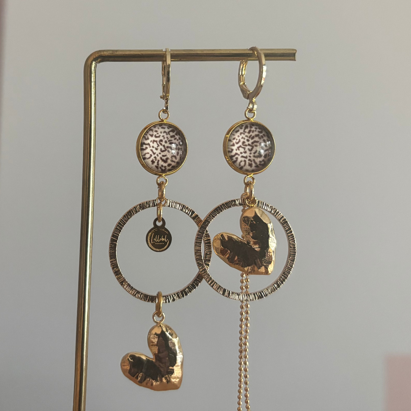 Asymmetrische 14k vergulde oorbellen Ivy met panterprint cabochon, gehamerde ringen, hartvormige bedel en kwastje, circa 6 cm lang