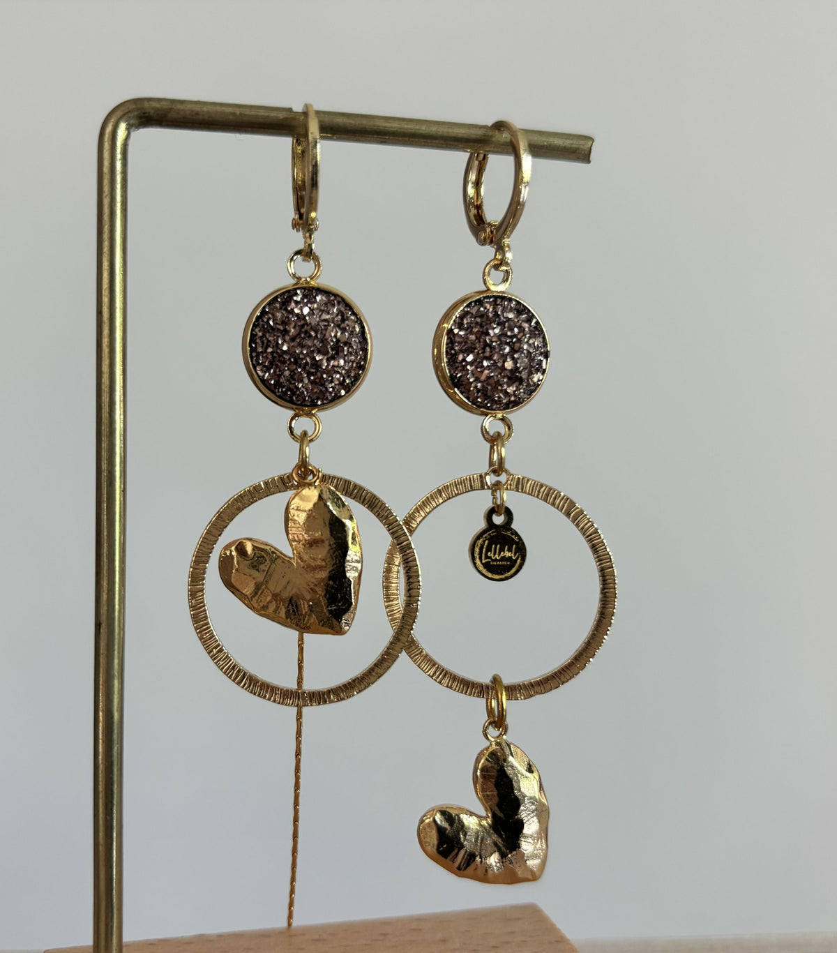 asymmetrische oorbellen met gehamerde harten, ringen en een strengetje. Gecombineerd met een rose kleurige cabochon