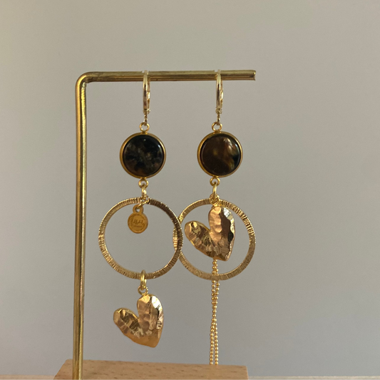 Asymmetrische 14k vergulde oorbellen met donkerbruine cabochon, gehamerde ringen, hartbedel en klein kwastje, ca. 6 cm lang.