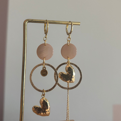 Asymmetrische 14k vergulde oorbellen Ivy met zachtroze cabochon, gehamerde ringen, hartvormige bedel en kwastje, circa 7 cm lang