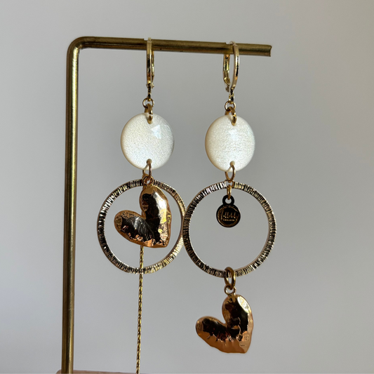Asymmetrische 14k vergulde oorbellen Ivy met witte parelmoer cabochon, gehamerde ringen, hartvormige bedel en kwastje, circa 7 cm lang