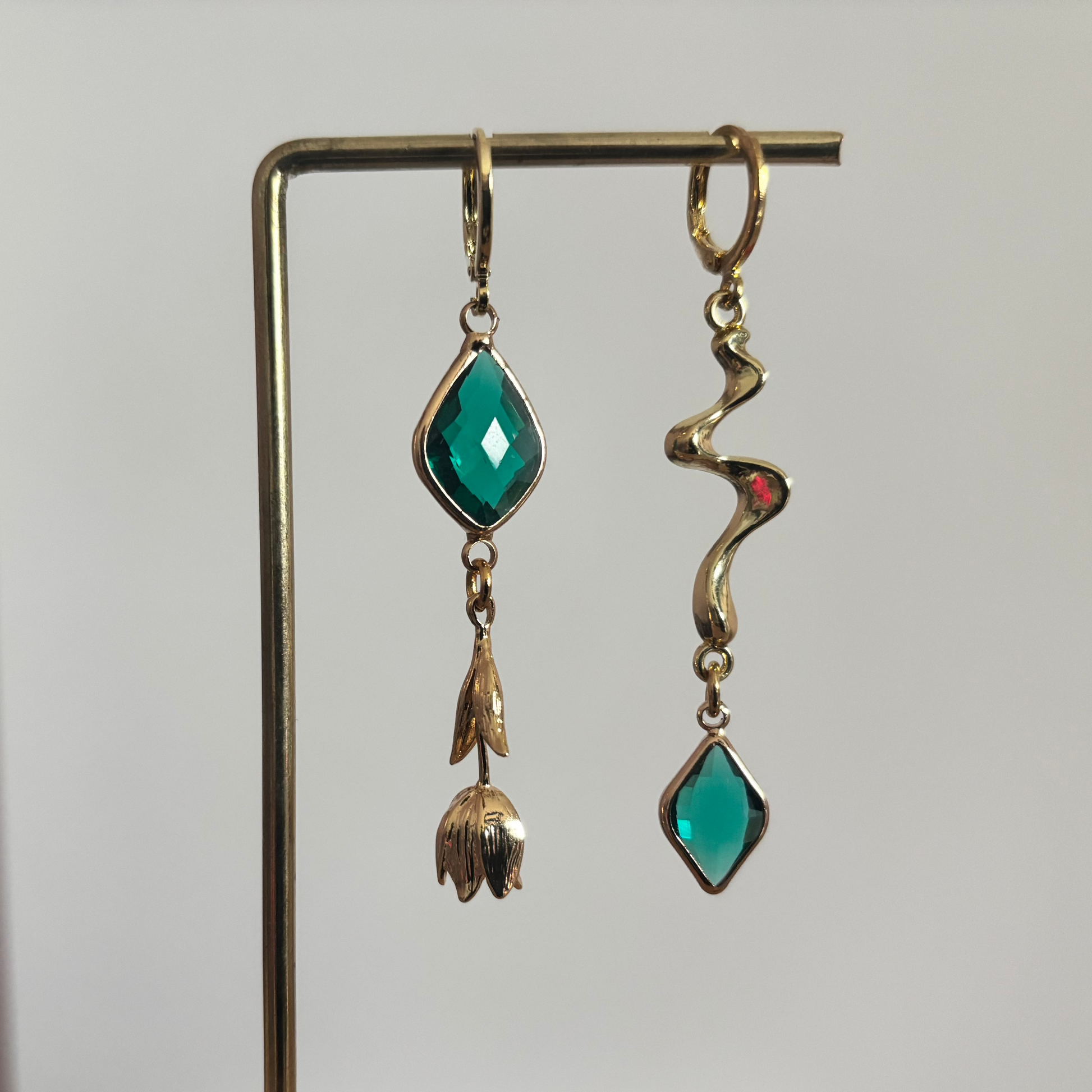 Asymmetrische 14k vergulde oorbellen 'Jade' met smaragdgroene stenen, een hanger in de vorm van een tulp en een gouden golvende bedel