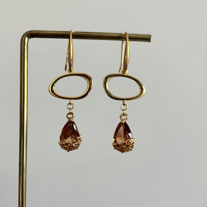 14k vergulde oorbellen Jinke met een liggende open ovale ring en een gefacetteerde amberkleurige kristal druppel.