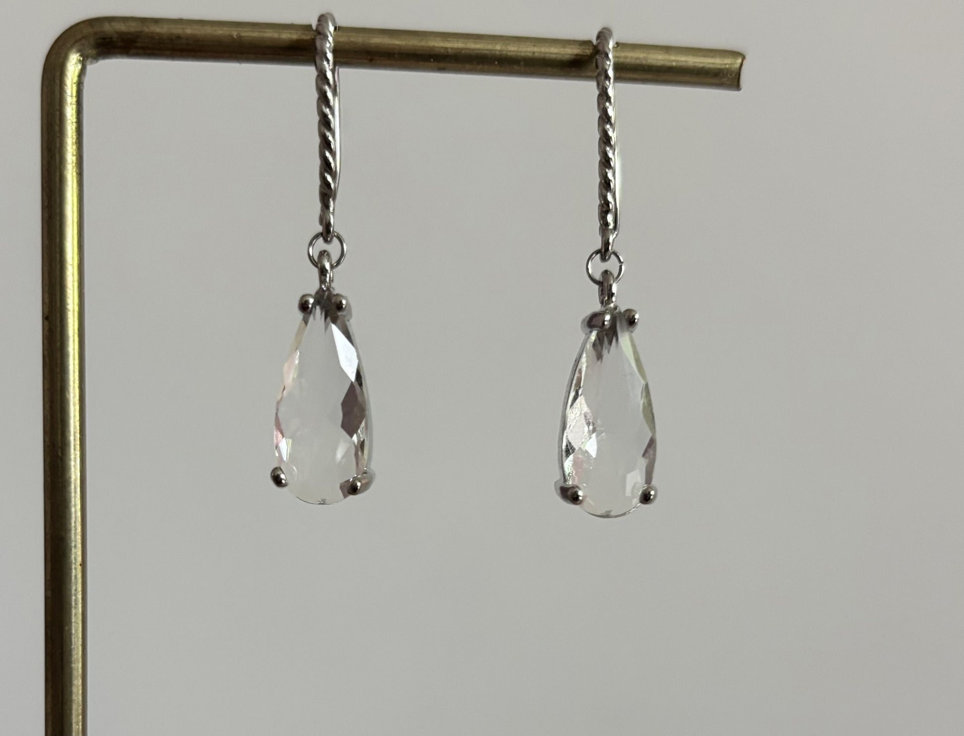 Kiek Clear oorbellen van verguld zilver met gedraaide oorhaken en een hangende, traanvormige heldere gefacetteerde glassteen.