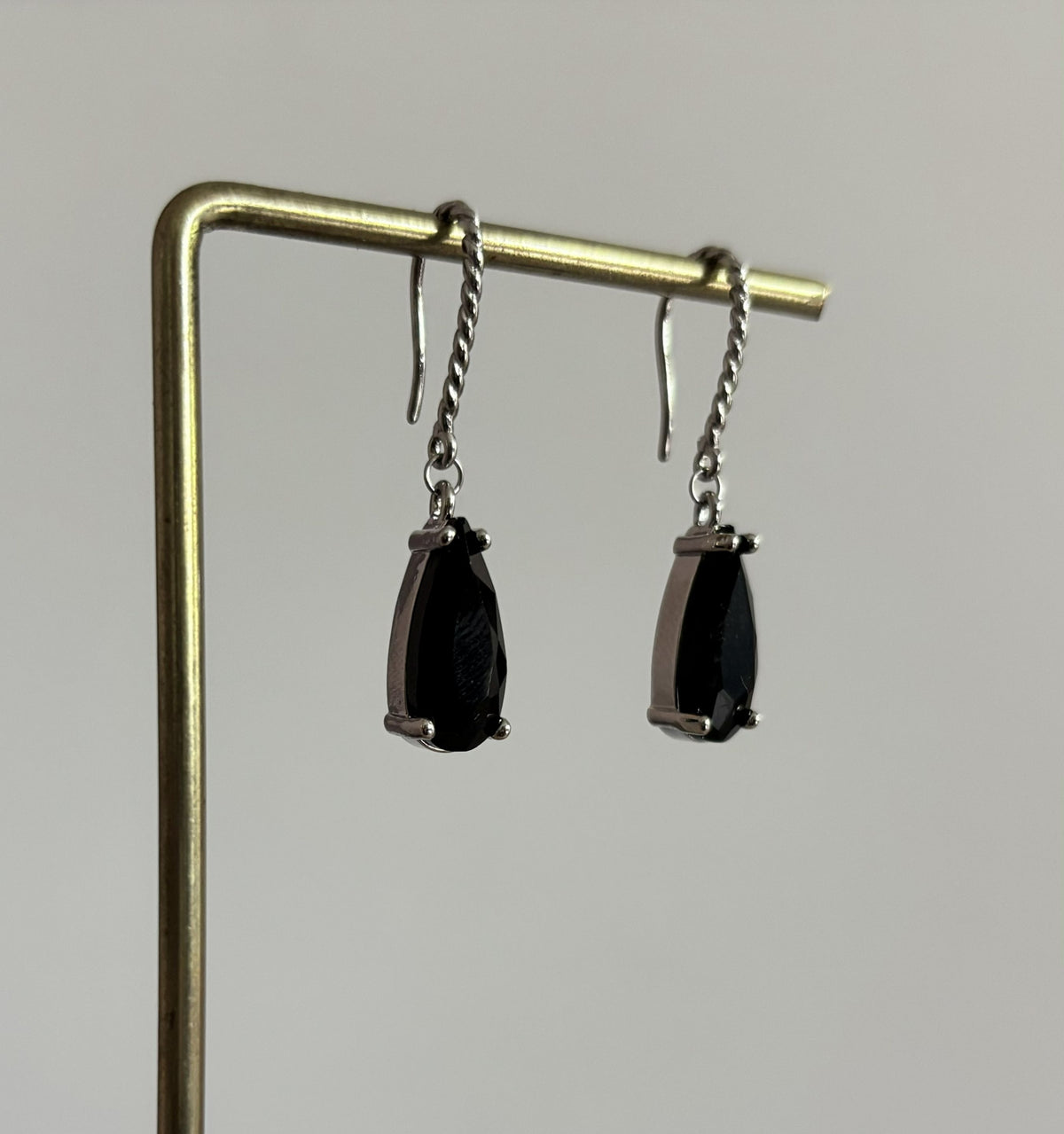 Kiek Zwart Zilver oorbellen van verguld zilver met gedraaide oorhaken en een hangende, traanvormige zwarte gefacetteerde glassteen.