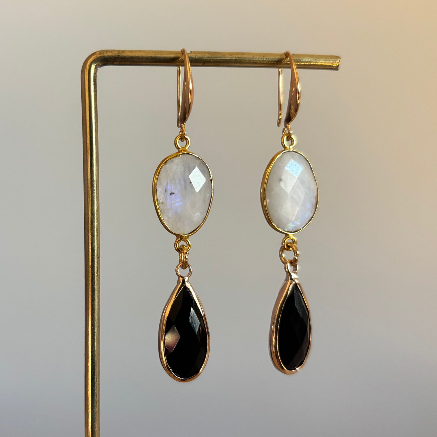 14k vergulde oorbellen met ovale maansteen en zwarte druppelvormige hangers."