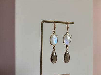 Lange 14k vergulde oorbellen 'Kyra' met een ovale melkwitte maansteen en een facetgeslepen taupe druppelhanger in een gouden omlijsting.