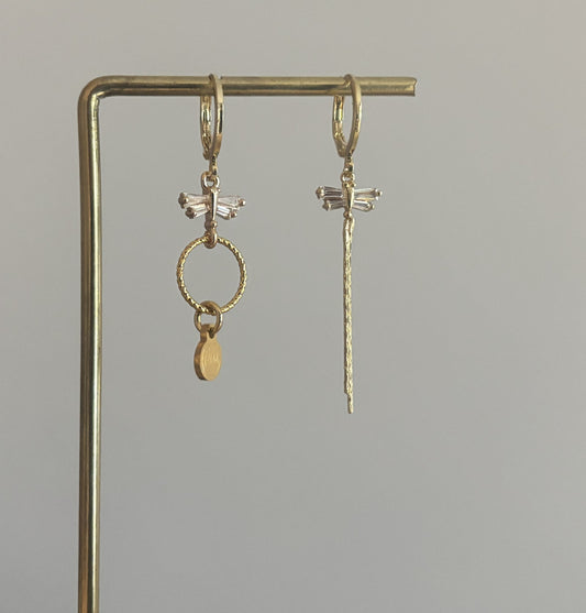 Asymmetrische oorbellen met zirkonia libelles, één met strengetje en één met minimalistische hanger en Lellebel-tag, circa 4 cm lang.