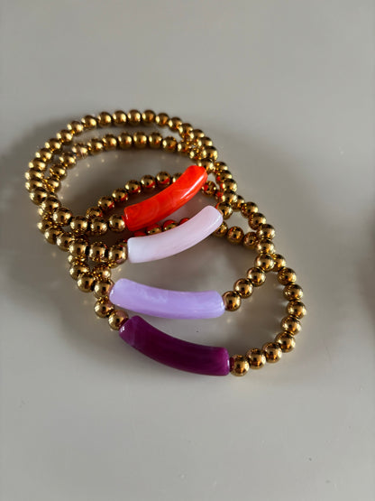 8k goldplated bolletjes en een grote, gebogen kunststof kraal met een subtiel gemarmerd effect in diverse kleuren zoals lila, fuchsia, oranje en mintgroen, paars, okergeel, koraal, zeegroen.