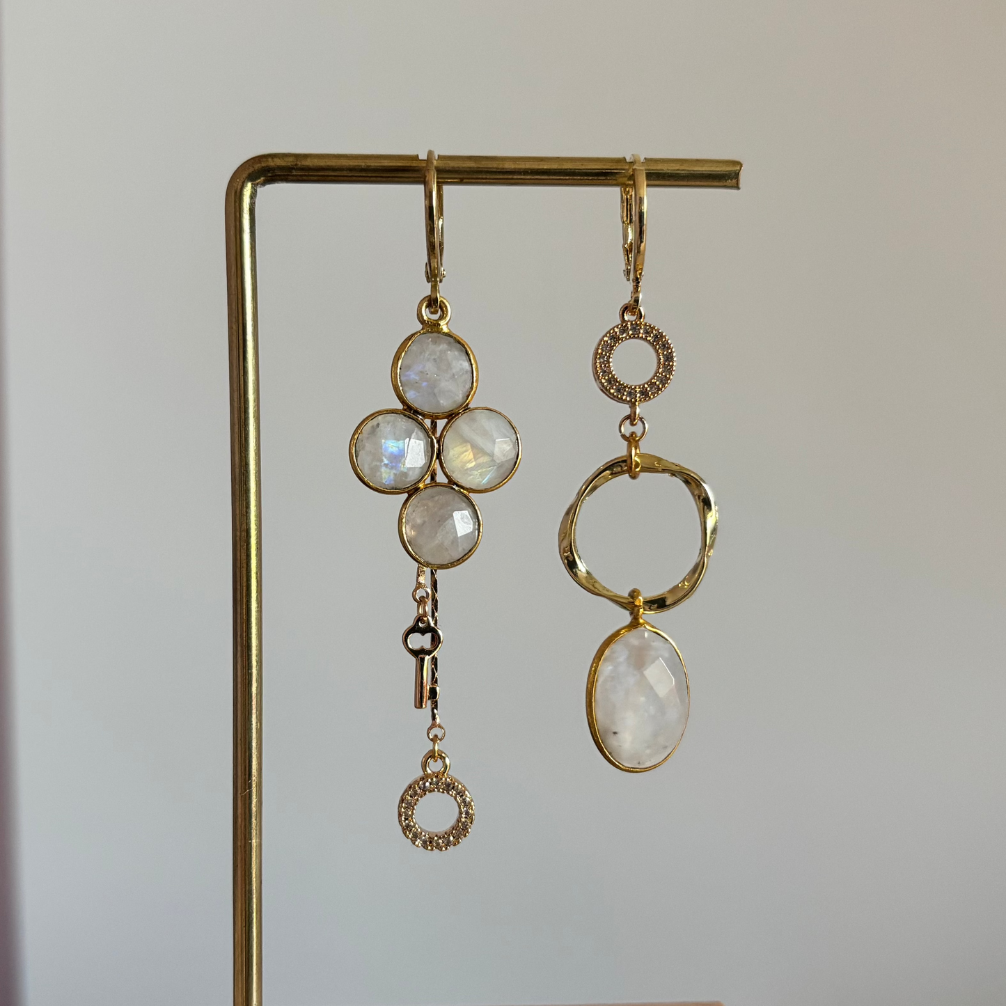 asymmetrisch paar met maanstenen, zirkonia ingelegde bedels en een 14k verguld sleuteltje