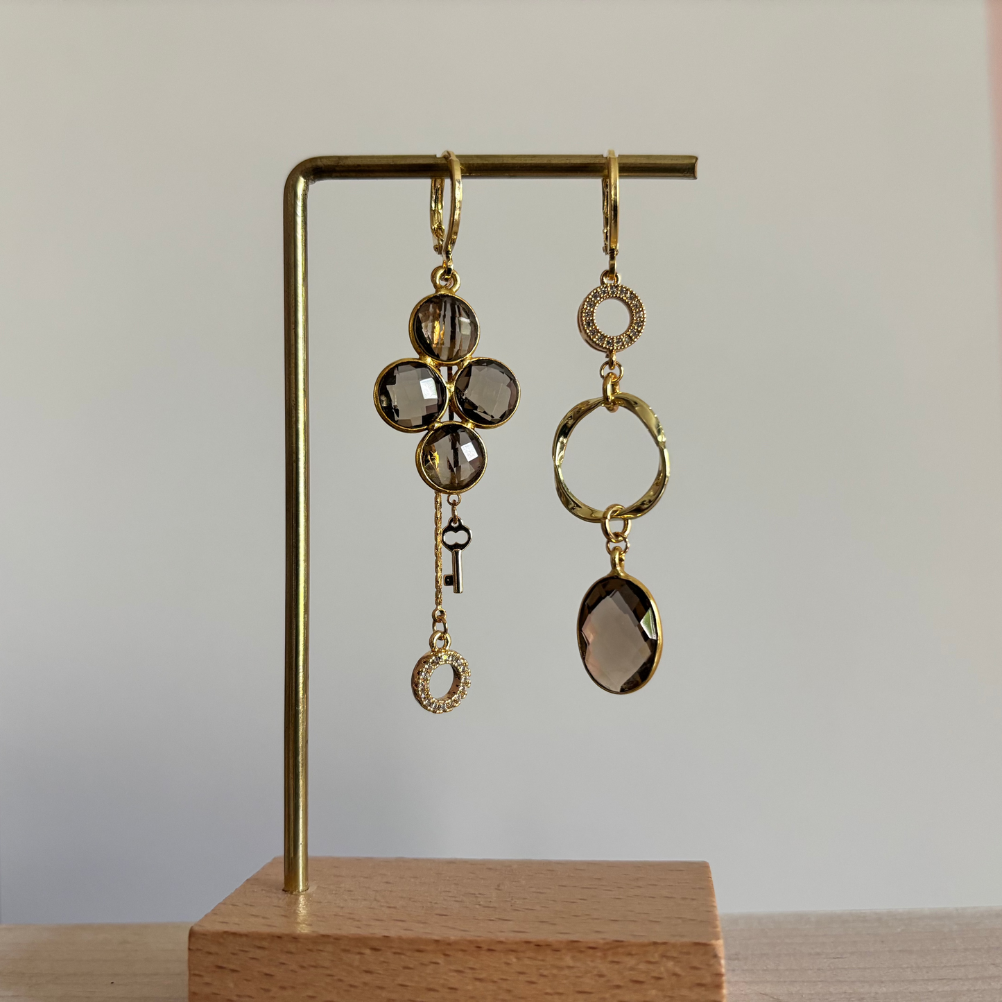 Lola asymmetrische oorbellen met taupekleurige glazen bedel, eigen ontworpen stenen, mini twisted ring, zirkonia steentjes en kwastje met sleuteltje, 14k verguld