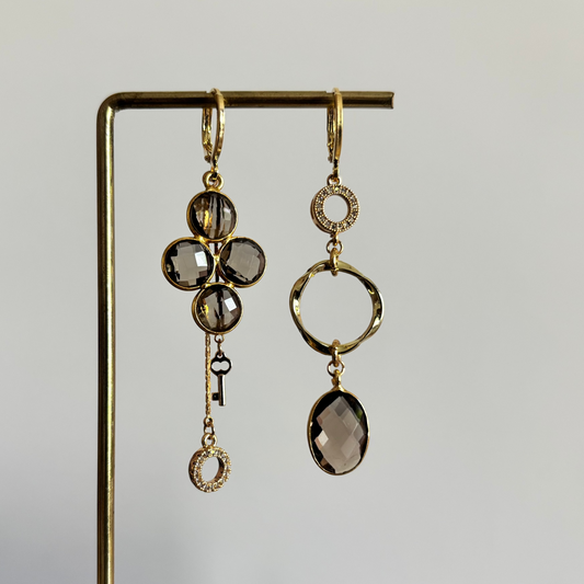 Lola asymmetrische oorbellen met taupekleurige glazen bedel, eigen ontworpen stenen, mini twisted ring, zirkonia steentjes en kwastje met sleuteltje, 14k verguld