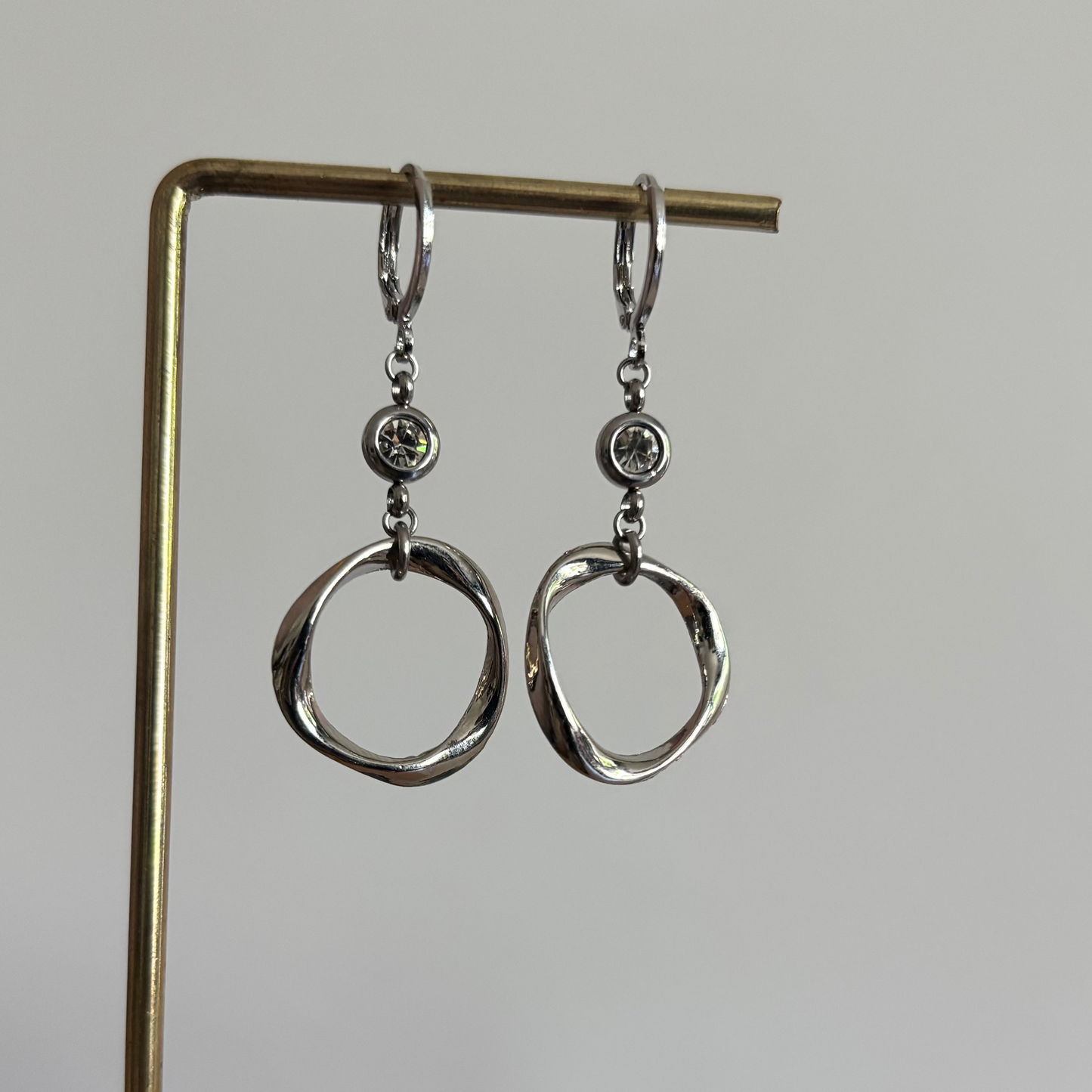 Zilveren RVS oorbellen Lonne met gedraaide cirkelhanger en zirkonia.