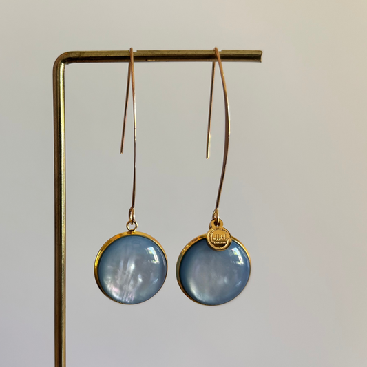 Lange goudkleurige oorbellen met een ronde, lichtblauwe cabochon bedel van 18 mm