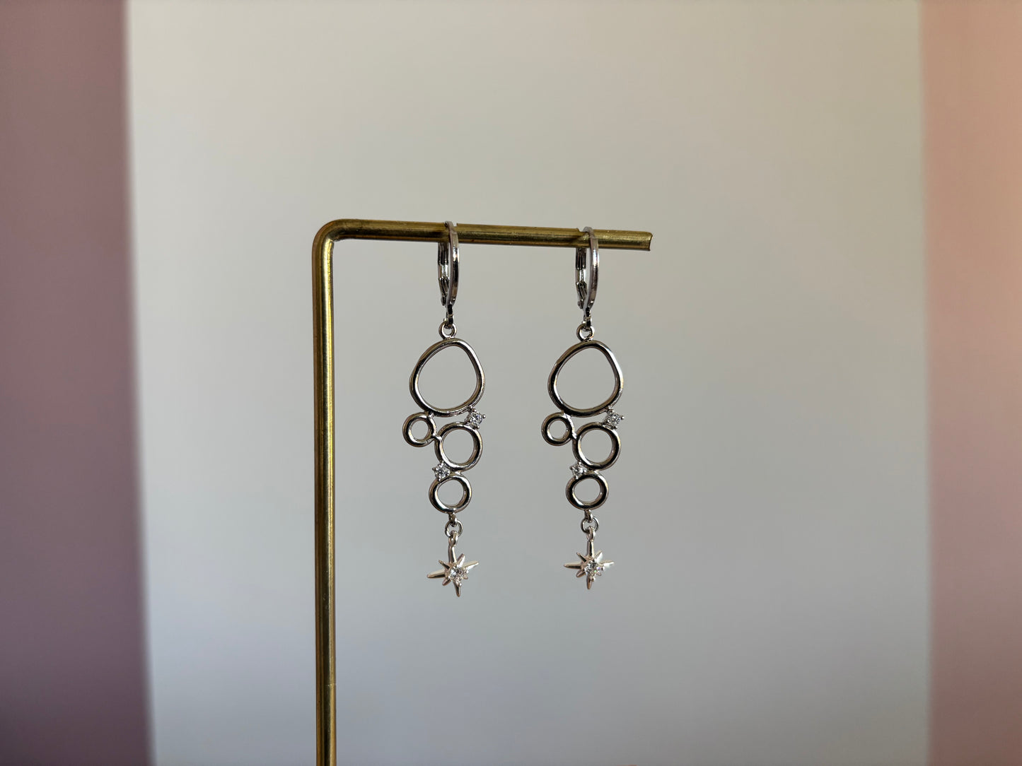 Minimalistische bedel met meerdere cirkeltjes met zirkonia en een klein zirkonia sterretje, circa 4 cm lang.