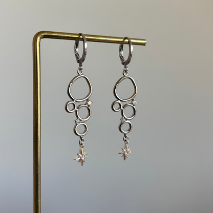 Minimalistische bedel met meerdere cirkeltjes met zirkonia en een klein zirkonia sterretje, circa 4 cm lang.